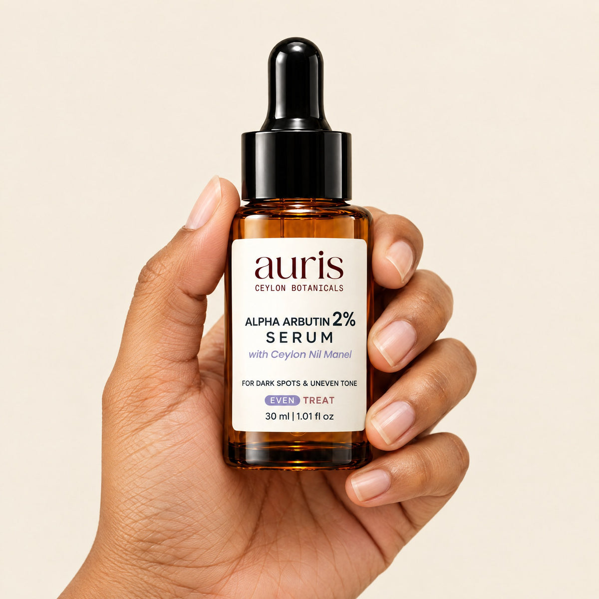 Auris EVEN Alpha Arbutin 2% Serum held in hand, label facing the camera
